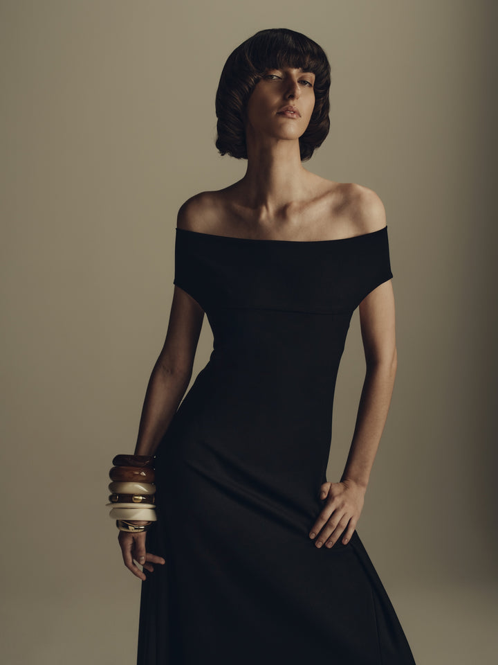 Black off-shoulder maxi dress styled with stacked bangles, evening luxury womenswear
