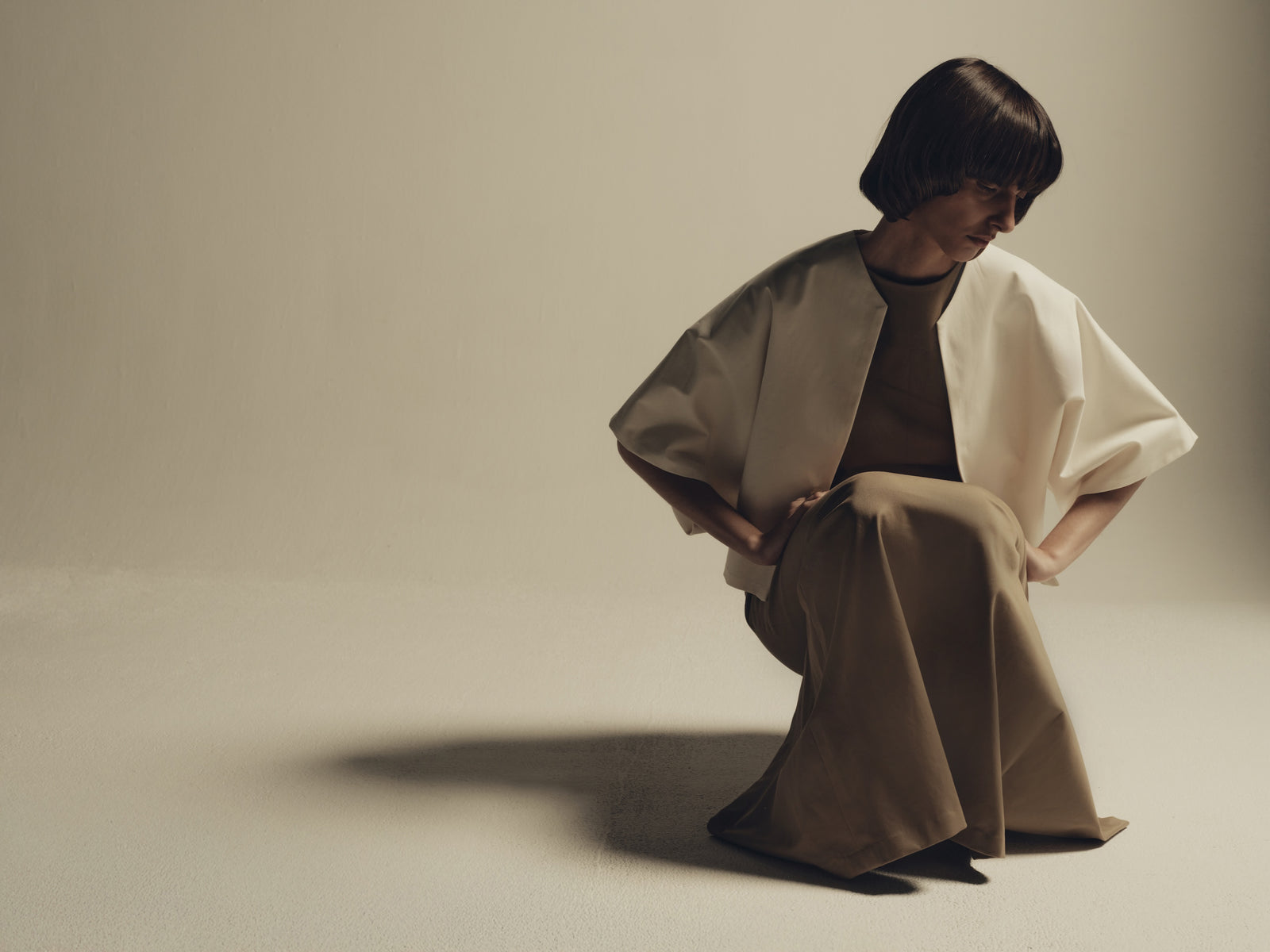 Ivory structured cape jacket over tailored wide-leg trousers, minimalist luxury womenswear