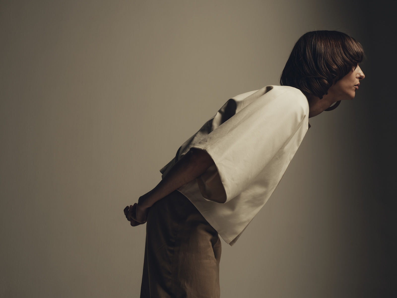 Ivory structured cape top styled over taupe minimalist trousers