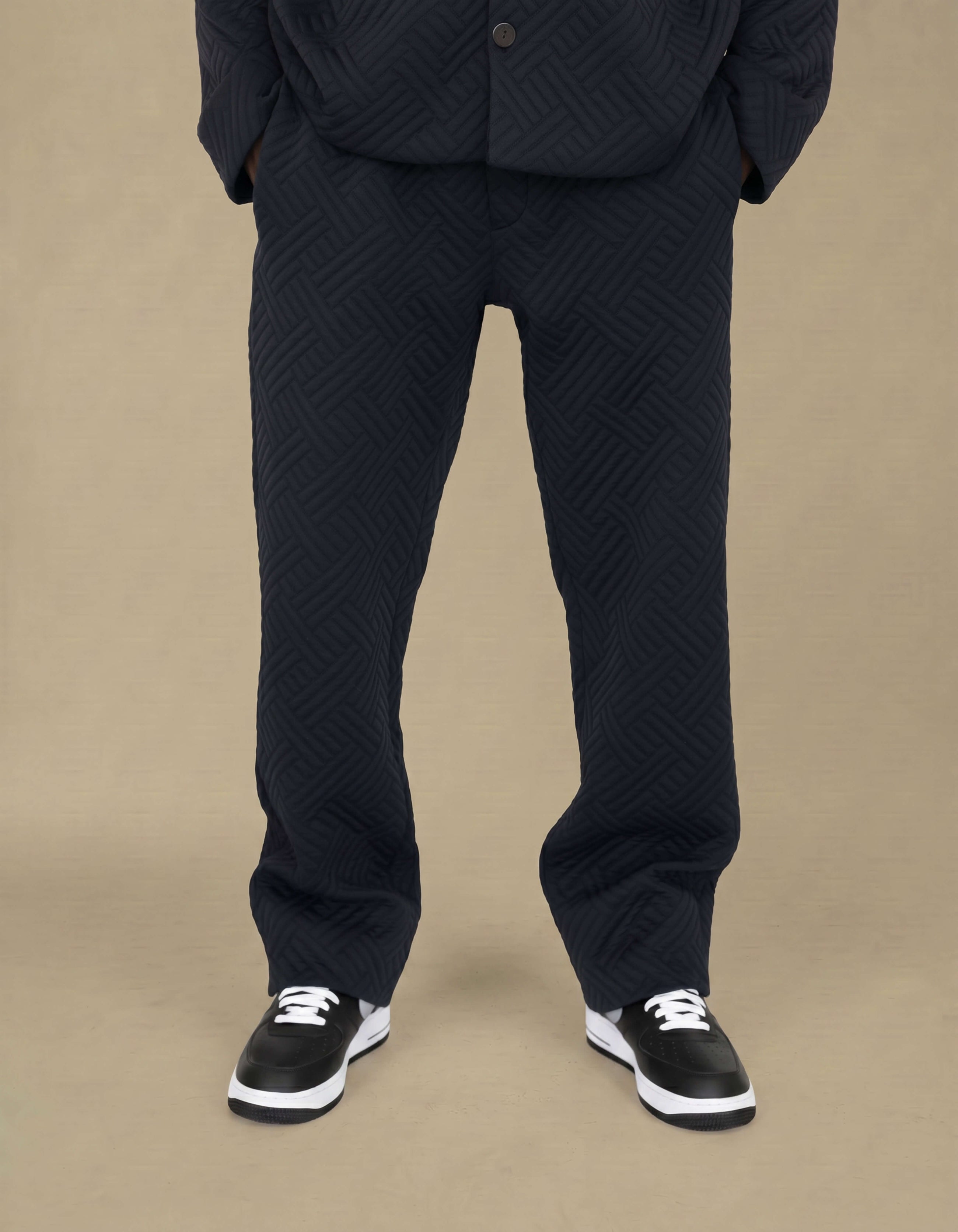 Navy quilted geometric jacquard straight-leg luxury trousers styled with sneakers
