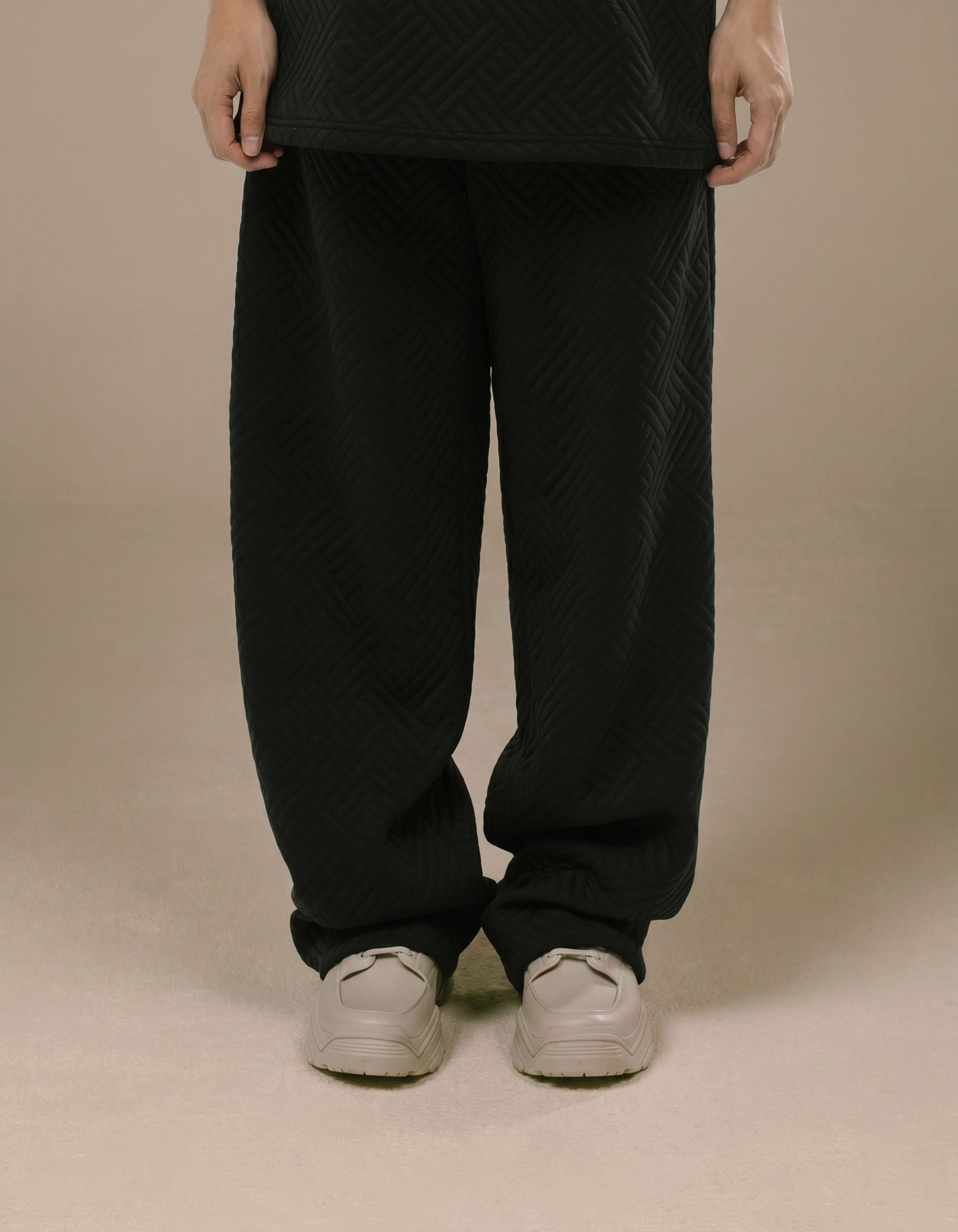 Black wide-leg quilted trousers with geometric textured pattern
