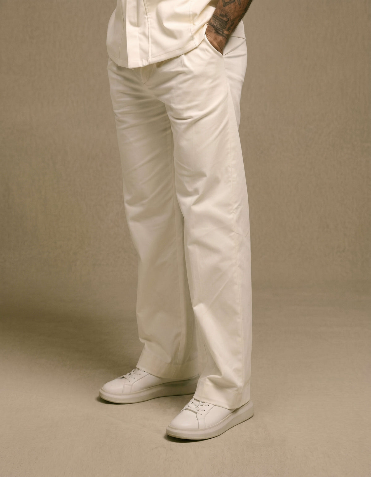 Ivory wide-leg tailored trousers styled with white sneakers
