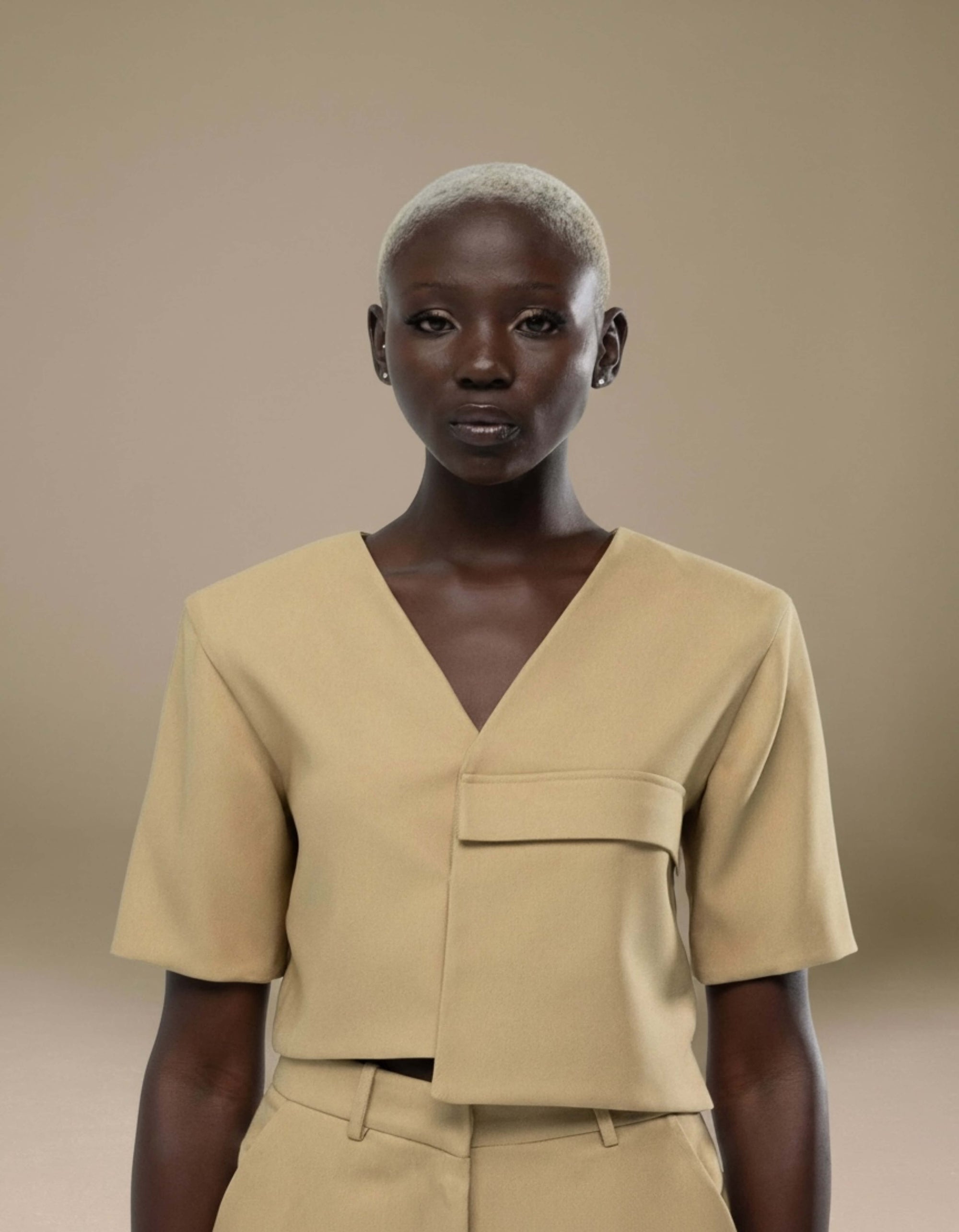 Tailored sand cropped top with V-neck and structured pocket detail

