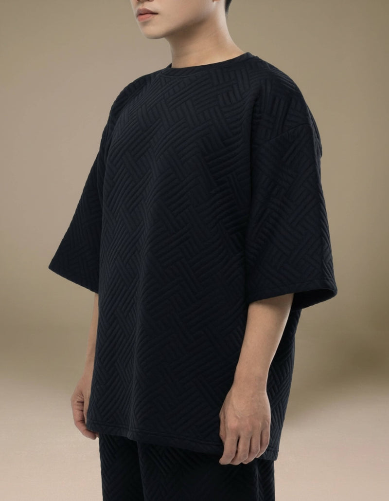 Oversized black quilted textured top with geometric woven pattern
