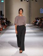 Model Wearing The Elamins Oversize T-Shirt In Taupe Styled With The Elamins Black Pleated Trousers On The Runway At TheEventDXB Fashion Show.
