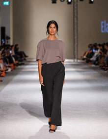 Model Wearing The Elamins Oversize T-Shirt In Taupe Styled With The Elamins Black Pleated Trousers On The Runway At TheEventDXB Fashion Show.
