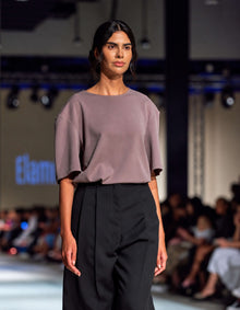 Elamins Oversize T-Shirt In Taupe Paired With The Elamins Black Pleated Trousers, Showing Its Round Neckline And Elbow-Length Sleeves At TheEventDXB Fashion Show.